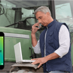 male farmer standing next to tractor and talking on the phone
