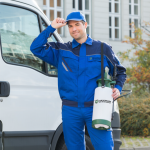 pest control technician holding chemical pesticide container posing